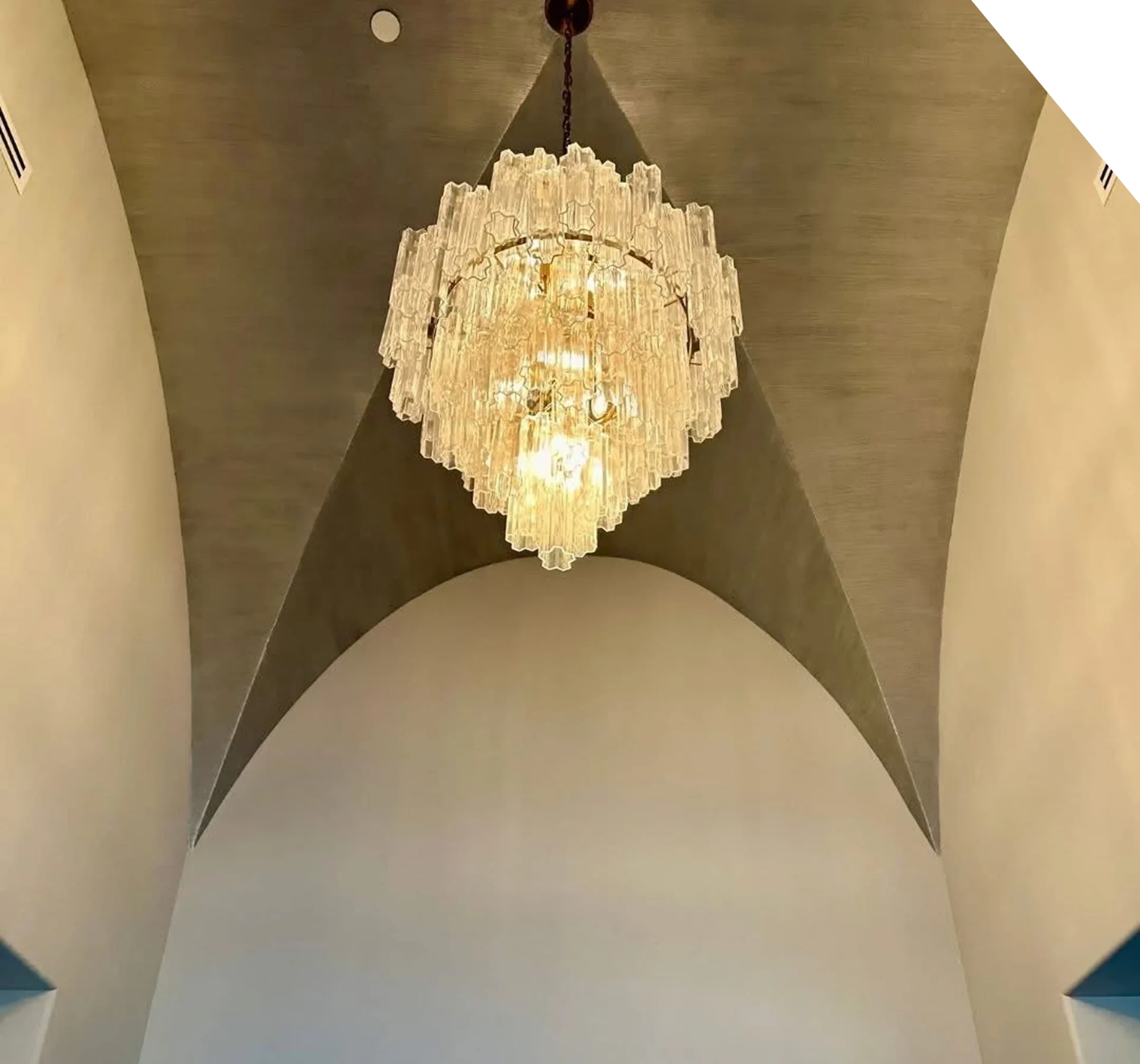Elegant crystal chandelier hanging from an arched ceiling.